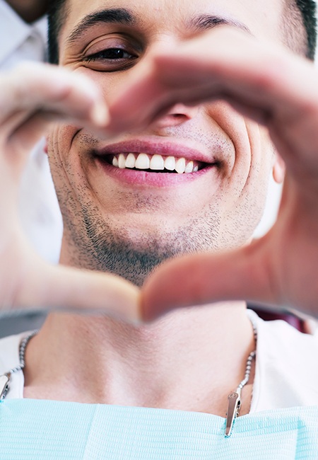 A male dental patient making a heart shape with his hands