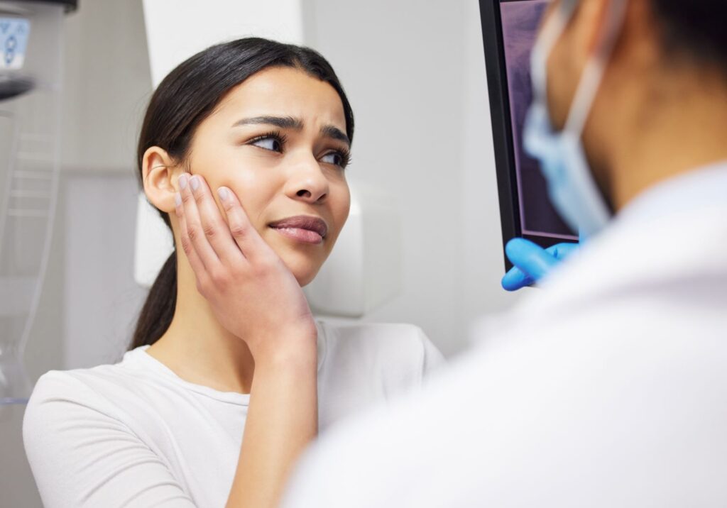 A woman clutching her jaw in pain.